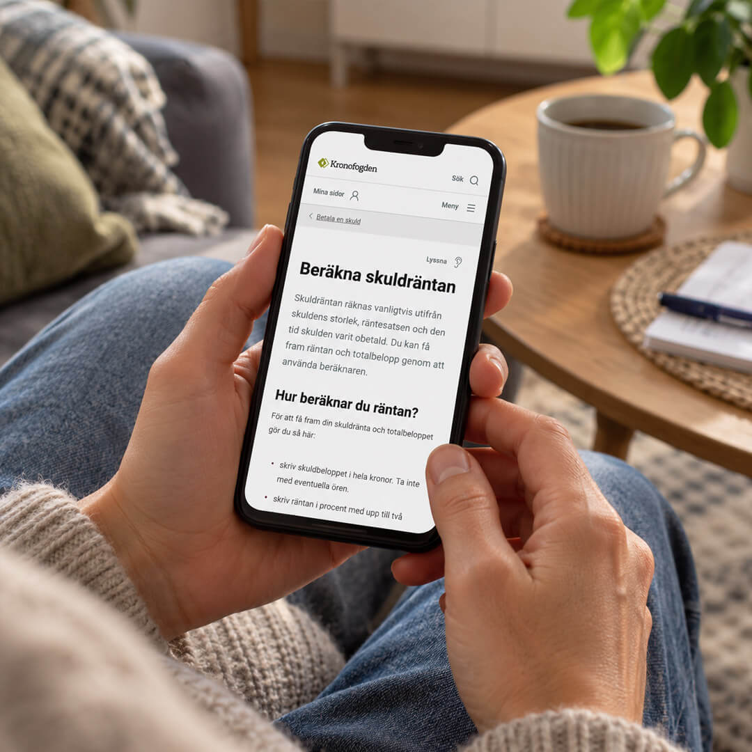 Person som räknar ut låneräntan på en mobiltelefon